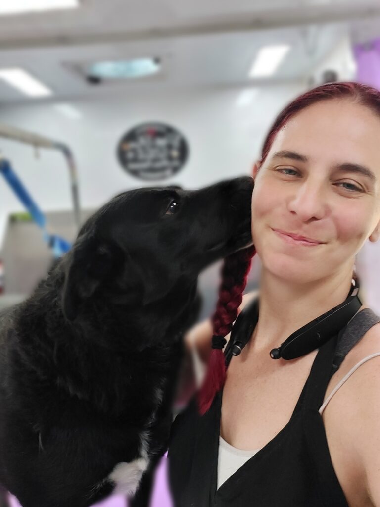 A woman and her dog are kissing in the gym.