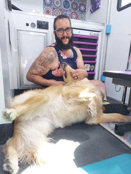 A man with a beard and glasses sitting next to a dog.